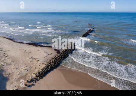 Luftaufnahme von Wellen, die gegen alte beschädigte Steinbrecher brechen pier im Meer Stockfoto