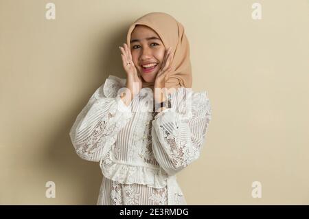 Junge asiatische Frau trägt Hijab schockiert Abdeckung Mund mit Händen für Fehler. Geheimes Konzept. Stockfoto
