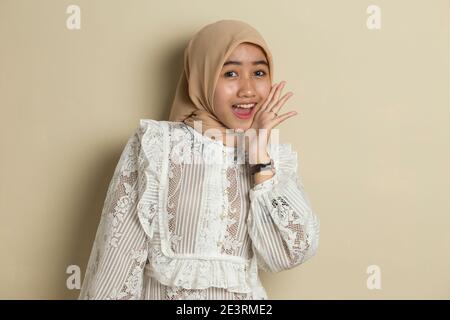 Junge asiatische Frau trägt Hijab schockiert Abdeckung Mund mit Händen für Fehler. Geheimes Konzept. Stockfoto