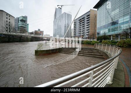 Manchester, Großbritannien, 20. Januar 2021. Ein Mitglied der Öffentlichkeit steht am Fluss Irwell im Zentrum von Manchester, nachdem Greater Manchester das letzte Gebiet wurde, das einen schweren Zwischenfall deklariert, da große Teile von Zentral- und Nordengland in den Weg des Sturms Christoph geraten waren. Kredit: Jon Super/Alamy Live Nachrichten. Stockfoto