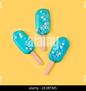 Blaue Minze Eis Eis Eis Eis Eis auf gelbem Hintergrund. Leckeres und erfrischendes Eis auf Stöcken. Minimales Sommerkonzept. Flach liegend. Stockfoto