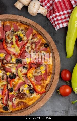 Pizzascheiben mit Thunfisch, Salami, Pilzen, Pepperoni und Gewürzen auf schwarzem Hintergrund, Kopierraum, Draufsicht. Stockfoto