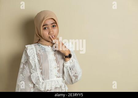 Junge asiatische Frau trägt Hijab schockiert Abdeckung Mund mit Händen für Fehler. Geheimes Konzept. Stockfoto