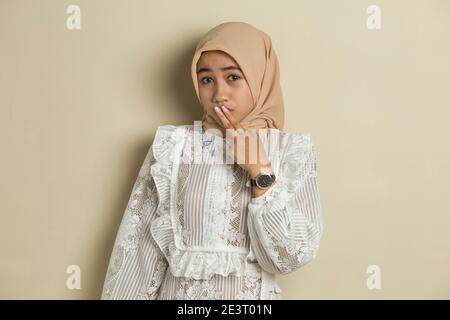 Junge asiatische Frau trägt Hijab schockiert Abdeckung Mund mit Händen für Fehler. Geheimes Konzept. Stockfoto