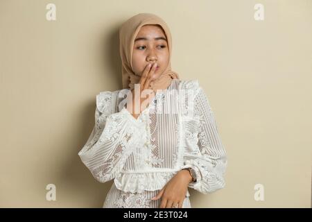 Junge asiatische Frau trägt Hijab schockiert Abdeckung Mund mit Händen für Fehler. Geheimes Konzept. Stockfoto