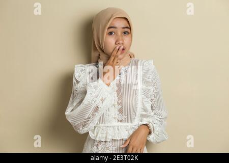 Junge asiatische Frau trägt Hijab schockiert Abdeckung Mund mit Händen für Fehler. Geheimes Konzept. Stockfoto