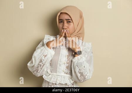 Junge asiatische Frau trägt Hijab schockiert Abdeckung Mund mit Händen für Fehler. Geheimes Konzept. Stockfoto