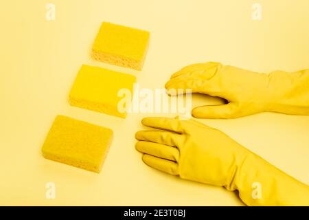 Hohe Sicht der Person in Gummihandschuhen und Schwämmen Auf gelbem Hintergrund Stockfoto