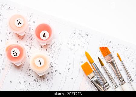 Der Pinsel des Künstlers und mehrfarbige Farbe für die Malerei auf der Färbung nach Zahlen Draufsicht der Tabelle Stockfoto