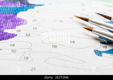 Der Pinsel des Künstlers und mehrfarbige Farbe für die Malerei auf der Färbung nach Zahlen Draufsicht der Tabelle Stockfoto