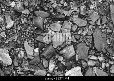 Draufsicht auf verschiedene lose und scharfe Felsen auf dem Geschliffen in schwarz und weiß Stockfoto