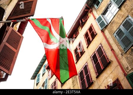 Bayonne, Frankreich. Winkende baskische Flagge in der engen Straße der Altstadt. Stockfoto