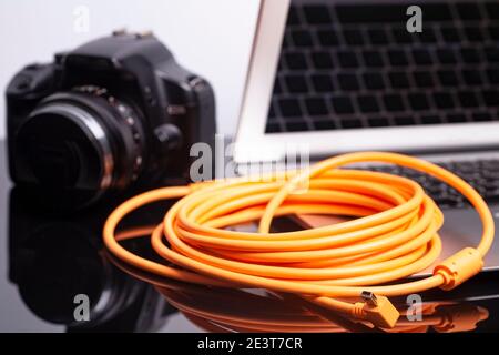 Digitale Fotokamera mit Laptop mit USB orange gerollten Kabel verbunden. Stockfoto