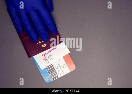 Reisen während der COVID-19-Pandemie, Hand halten Pass mit Flugticket, covid-19 geimpfte Karte mit 'Ja'-Zeichen auf grauem Hintergrund, Flughafen se Stockfoto