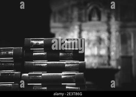 Gebetsbücher und verschwommener Altar im Hintergrund. Religionskonzept. Selektiver Fokus. Historisches Foto in Schwarzweiß Stockfoto