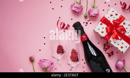 Konzept für Banner, Grußkarte für Valentinstag. Flasche Champagner Wein, Gläser Mit glitzernden Konfetti in Form von Herz, Rosen, Serpentin und Stockfoto