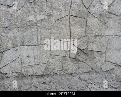 Graue Betonwand mit zerbröckelndem gemustertem Putz. Textur nicht nahtlos Stockfoto