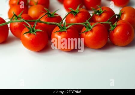 Bedeckt mit Wassertropfen, frische Tomaten mit Zweige auf weißem Hintergrund, Gemüse Stockfoto
