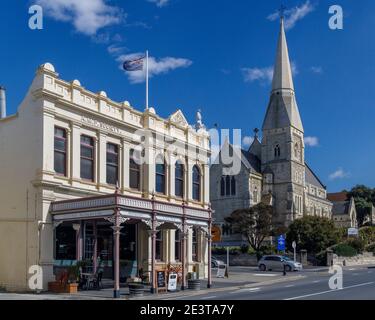 1871 A.M.P. Gesellschaftsgebäude, das heute von Cafés genutzt wird, mit der anglikanischen Kirche St. Luke im Hintergrund. Oamaru, Südinsel, Neuseeland. Stockfoto