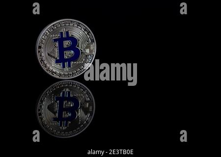 Bitcoin Nahaufnahme auf schwarzem Hintergrund mit reflektierender Oberfläche. Kryptowährung und elektronische Zahlungen. Stockfoto