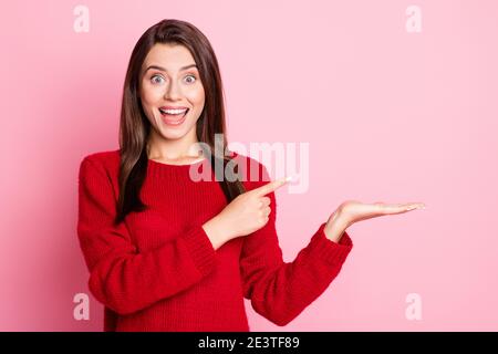 Foto-Porträt von schockiert überrascht Mädchen mit brünetten Haaren erstaunt Gesicht zeigt auf leeren Raum lächelnd isoliert auf rosa Farbe Hintergrund Stockfoto