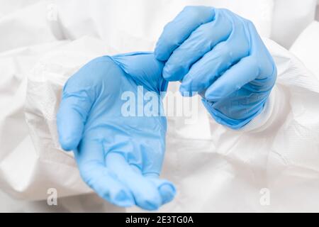 Arzt oder Krankenschwester im Schutzanzug, der Gummi aufsetzt Blaue Handschuhe vor der Arbeit mit Coronavirus-Patienten oder Testproben Oder Impfungen Stockfoto