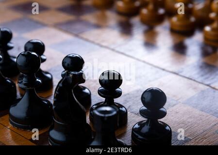 Schach auf einem Schachbrett, schwarze Bauern gegen Weiß. Stockfoto