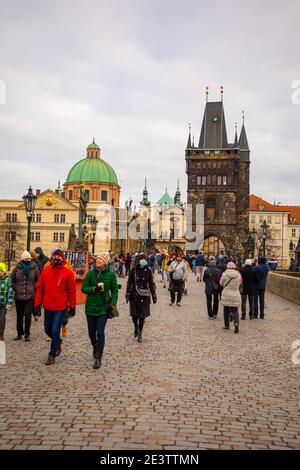 PRAG, TSCHECHISCHE REPUBLIK - 26. DEZEMBER 2020: Menschen auf der Karlsbrücke, einige mit Gesichtsmasken, Coronavirus-Pandemie Stockfoto