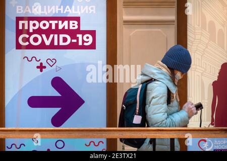 Moskau, Russland. 20. Januar 2021 Bürger mit Gesichtsmasken stehen in der Schlange vor einer mobilen Impfeinheit COVID-19 im KAUGUMMI-Kaufhaus im Zentrum von Moskau, Russland. Seit Januar 18 hat Russland mit dem Sputnik V-Impfstoff mit einer Massenimpfung gegen die neuartige Coronavirus-Infektion COVID-19 begonnen. Auf dem Banner steht: „COVID-19-Impfung“ Stockfoto