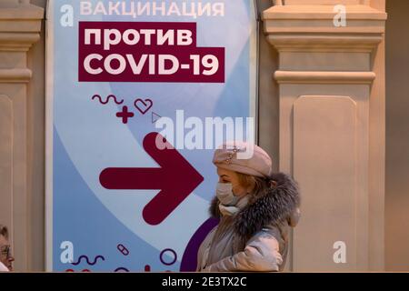 Moskau, Russland. 20. Januar 2021 Bürger mit Gesichtsmasken stehen in der Schlange vor einer mobilen Impfeinheit COVID-19 im KAUGUMMI-Kaufhaus im Zentrum von Moskau, Russland. Seit Januar 18 hat Russland mit dem Sputnik V-Impfstoff mit einer Massenimpfung gegen die neuartige Coronavirus-Infektion COVID-19 begonnen. Auf dem Banner steht: „COVID-19-Impfung“ Stockfoto