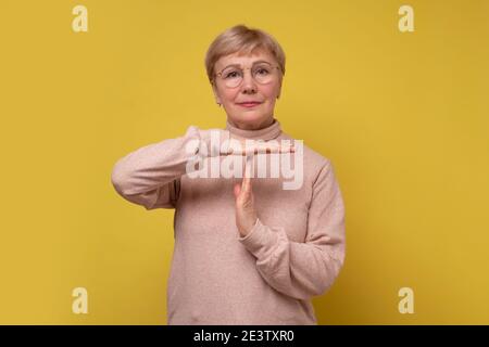 Seriöse Frau zeigt Auszeit Geste, brauchen mehr Zeit für die Arbeit, um Pause bitten. Studioaufnahme Stockfoto