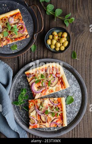 Hausgemachte gesunde Shiitake Pilzpizza mit Scheiben mit grünen Oliven, Käse, rote Zwiebel und Oregano auf rustikalem Holzhintergrund gekrönt Stockfoto