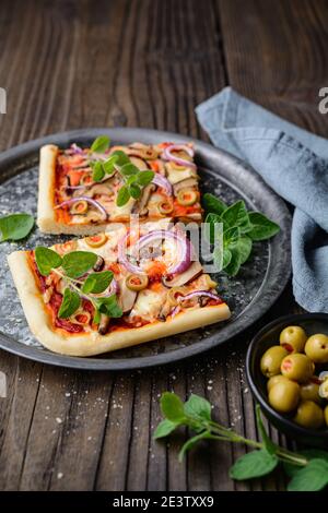 Hausgemachte gesunde Shiitake Pilzpizza mit Scheiben mit grünen Oliven, Käse, rote Zwiebel und Oregano auf rustikalem Holzhintergrund gekrönt Stockfoto