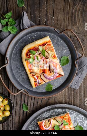 Hausgemachte gesunde Shiitake Pilzpizza mit Scheiben mit grünen Oliven, Käse, rote Zwiebel und Oregano auf rustikalem Holzhintergrund gekrönt Stockfoto