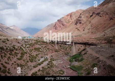 Alte verlassene Eisenbahnbrücke über den Fluss Las Cuevas in der Nähe von Puente del Inca Dorf in Andes MounRains. Mendoza Provinz, Argentinien Stockfoto