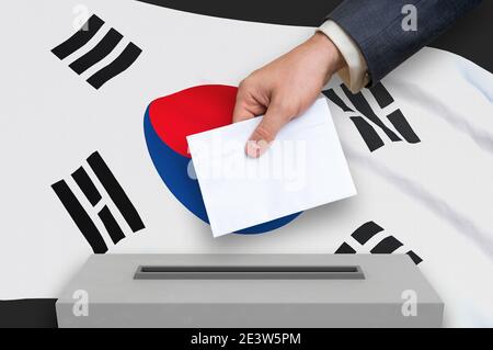 Wahl in Südkorea - Abstimmung an der Wahlurne. Die Hand des Menschen stellt seine Stimme in die Wahlurne. 3D-Darstellung. Stockfoto