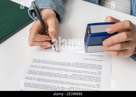 Geschäftsfrau, die im Büro auf Dokumente stempelt - Vertragskonzept unterzeichnen Stockfoto