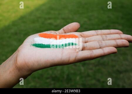 Weibliche Putting Rangoli auf Palme anlässlich der indischen republik Tag Feier zu Hause Lockdown. Dreifarbiges Design mit indischer Flagge, das Freiheit zeigt, Stockfoto