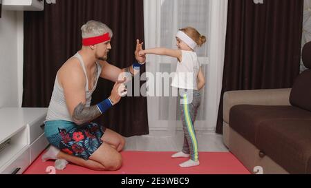 Retro-Stil athletischen Mann Trainer trainieren mit Kind Kind Mädchen. Grauhaarige bärtige Sportler Kerl Trainer Vater tun Boxen Übungen mit Tochter zu Hause auf Matte. Indoor Familien Sport Workout Stockfoto