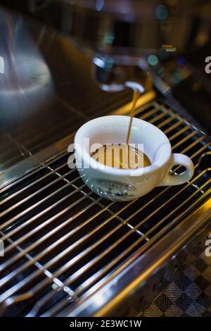 Frischen espresso tropft vom portafilter der Kaffeemaschine in weißen Schale Stockfoto