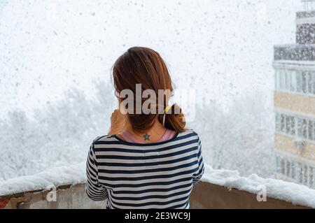 Ein junges Mädchen in einem gestreiften Pullover steht allein auf Ein Balkon Stockfoto