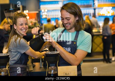 Glückliche weibliche und männliche Baristas Gießen Kaffee durch Filter Stockfoto