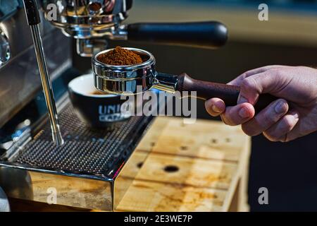 Hand halten Portafilter mit gemahlenem Kaffee Espresso Maschine Stockfoto
