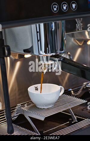 Frischen espresso tropft vom portafilter der Kaffeemaschine in weißen Schale Stockfoto