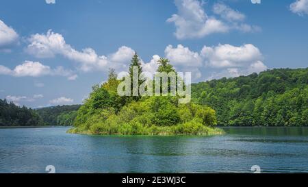 Kleine Insel auf sauberen See umgeben von Hügeln und grünen üppigen Wald, Plitvicer Seen Nationalpark UNESCO-Weltkulturerbe in Kroatien Stockfoto