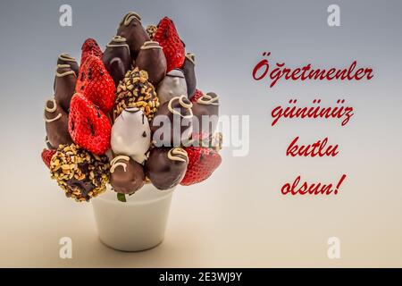 Happy Teacher's Day Grußkarte in türkischer Sprache mit rotem Schriftzug, der Ogretmenler gunuz kutlu olsun liest; Strauß essbarer Blumen, arrangem Stockfoto