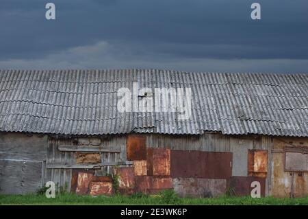 Alte verwitterte Holzhütte, grau überzogene Holz-Boarding-Hütte Wand, geflickte Bretter, verrostete Metallplatten, rostige Farbstruktur, Moltescape Panorama Stockfoto