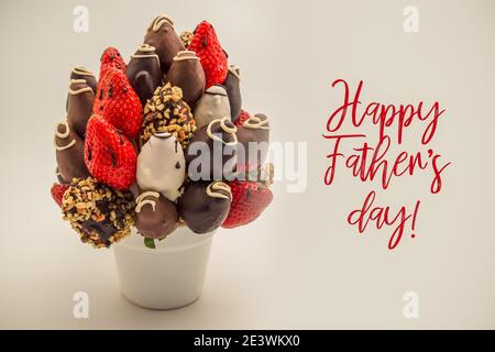 Glückwunschkarte zum Vatertag mit roten Schriftzügen; EIN Bündel essbarer Blumen, Arrangement von in Schokolade getauchten Erdbeeren isoliert auf Weiß Stockfoto