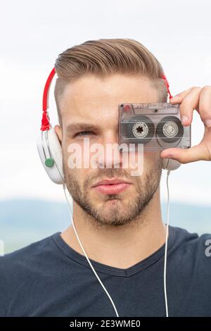 Mann hört Musik mit Kassette und Kopfhörer. Emotionaler Porträtmann. Retro-Player. Junger bärtiger Mann im Stil der 90er Jahre Stockfoto