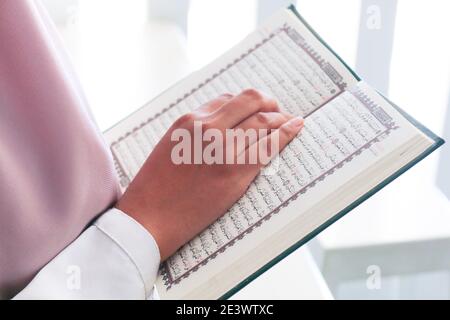 Nahaufnahme der Hand beim Lesen des Heiligen Quran in der Moschee. Selektiver Fokus. Stockfoto